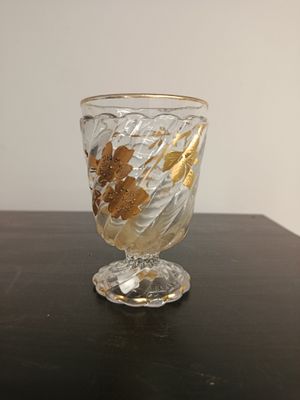 a glass vase with gold leaves on it on a table