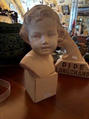 a statue of a child sitting on a table next to a box