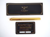 a gold pen and a black business card on a white surface