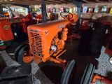 an orange tractor sitting in a barn with other tractors