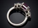 a close up of a ring with a purple stone surrounded by white diamonds