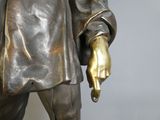 une statue représentant un homme tenant un couteau dans une main et un autre couteau dans l'autre