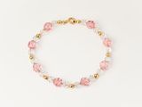 a pink and white bracelet with gold beads on a white background