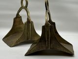 une paire de serre-livres anciens en laiton en forme de cloche, sur fond blanc
