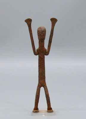 une petite figurine en bronze représentant un homme les mains levées