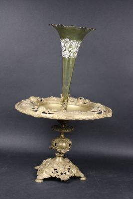 une plaque en laiton ancien sur laquelle est posé un vase en verre vert