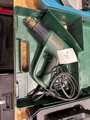 une boîte verte contenant une perceuse filaire et un cordon d'alimentation