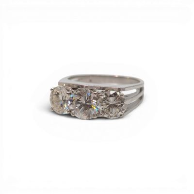 une image représentant une bague en diamant à trois pierres sur fond blanc