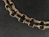 a close up of a black and gold necklace on a black surface