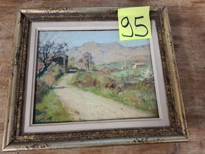 une peinture à l'huile représentant un chemin de terre, encadrée et posée sur une table en bois