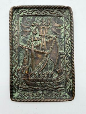 a close up of a metal plaque with a ship on it
