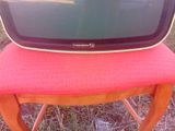 un petit téléviseur posé sur une chaise rouge