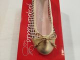 des ballerines dorées ornées d'un nœud, posées sur une boîte rouge