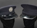 pair of police hats on mannequin heads on a black background