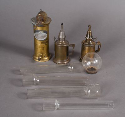 trois types différents d'objets en verre et en laiton posés sur une surface grise