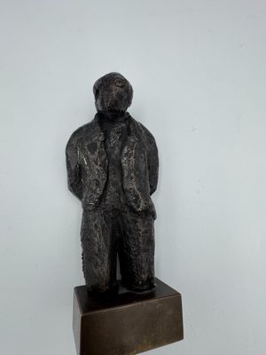 statue of a man in a suit and tie standing on a wooden block