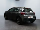 the back of a grey car in a showroom with a clock on the wall