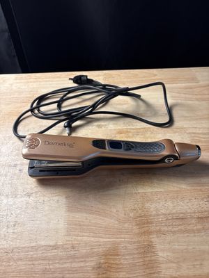le fer à lisser est posé sur une table en bois, à côté d'une paire de lunettes