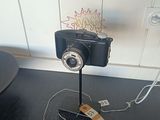 une image représentant un appareil photo posé sur un trépied, avec une étiquette de prix accrochée dessus