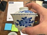 a person holding a blue and white tea pot on a desk