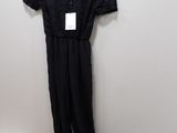 black lace jumpsuits and shoes on a hanger in front of a white wall