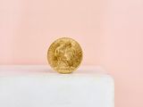 a gold coin sitting on top of a white pedestal