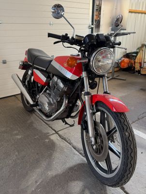 a red and black motorcycle parked in front of a garage