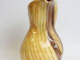 a yellow and brown vase sitting on a white surface