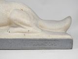 statue of a cat laying on a base with its head on the ground