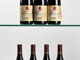six bouteilles de vin sont posées sur une étagère en verre devant un fond blanc