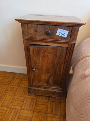 a small table with a clock on it next to a bed