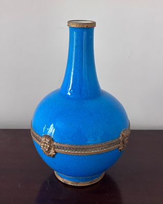 un vase bleu posé sur une table en bois, avec un mur blanc en arrière-plan