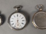 Trois types différents de montres de poche sont exposés sur une table