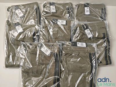 six paires de pantalons emballées dans du plastique, posées sur une table