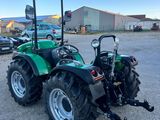 un tracteur vert garé sur un parking à côté d'un bâtiment