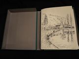 someone is drawing a picture in a book on a table