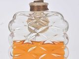 perfume bottle with orange liquid and a white top with a mouse on top