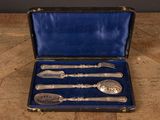 un service d'argenterie ancienne dans un coffret bleu, posé sur une table en bois