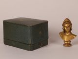 une photo représentant une petite statue de femme à côté d'une boîte
