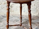 a small wooden table with a wooden top on a brick floor