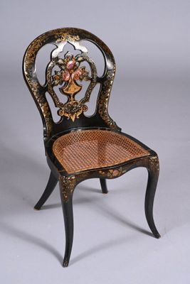 a black chair with a wicker seat and a basket on the back