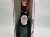 une bouteille de champagne vide dans une boîte rose posée sur une surface blanche