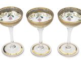 four wine glasses with gold rims and a flower design