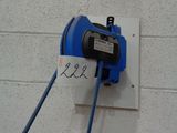 a blue cord plugged into a wall with a sign on it