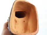 a hand holding a wooden vase with a hole in it