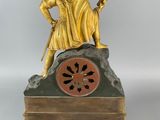 a gold statue of a man sitting on top of a clock