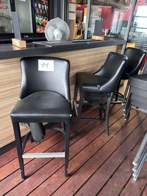 deux chaises noires posées devant un bar, avec un ventilateur en arrière-plan
