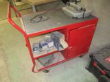 un chariot rouge sur lequel est posée une machine, dans un garage