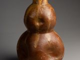 un vase marron posé sur une table près d'un mur gris