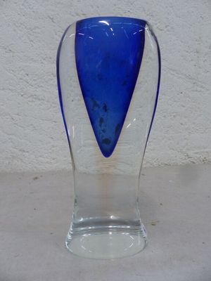 un vase en verre bleu posé sur une table blanche